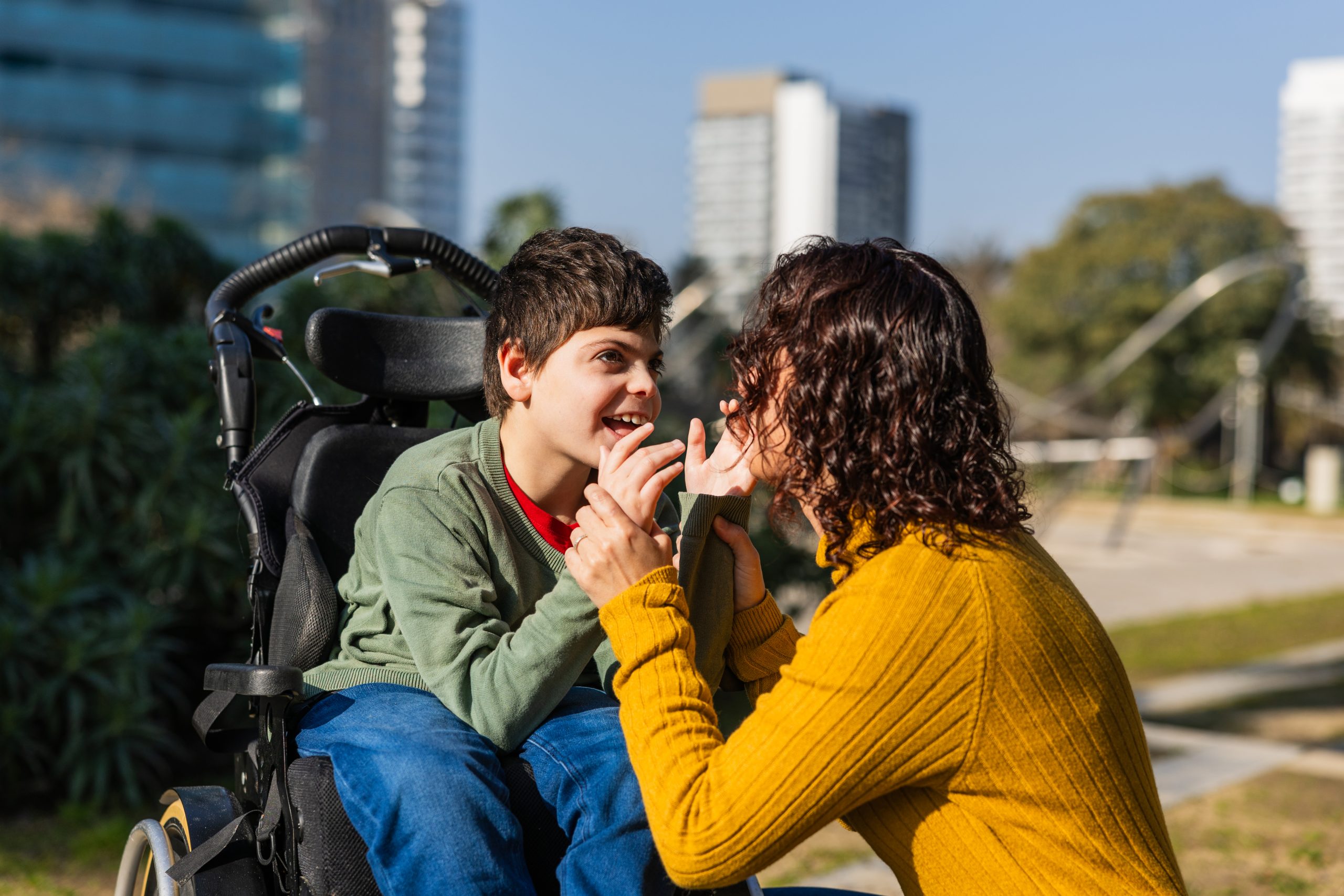 Happy child in wheelchair playing with mother outdoors Happy child in wheelchair playing with mother outdoors